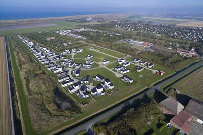 Luchtfoto van vakantiehuizen op Roompot Vakantiepark Callassande en de Noordzee aan de horizon