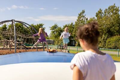 Kinderen springen op de airtrampoline in de speeltuin op Roompot Vakantiepark Callassande
