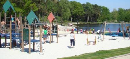 Kinderen spelen in de speeltuin naast het meer op vakantiepark EuroParcs Brunssummerheide