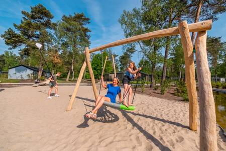 Kinderen spelen op de schommel in een speeltuin op vakantiepark EuroParcs De Hooge Veluwe