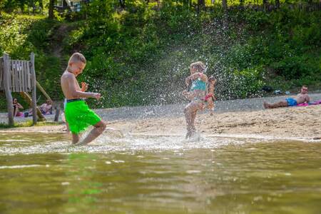 Kinderen spelen in het water van het strandbad van vakantiepark EuroParcs Maasduinen