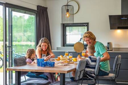 Gezin aan het ontbijten in de keuken van een vakantiehuis op vakantiepark EuroParcs Maasduinen