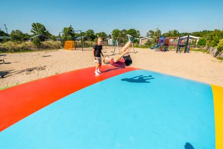 Kinderen springen op de airtrampoline in de speeltuin op vakantiepark EuroParcs Poort van Zeeland