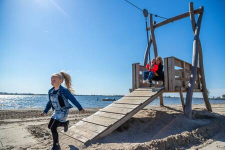 Kinderen in een speeltuin op het strand aan het Veluwemeer op vakantiepark EuroParcs Zuiderzee