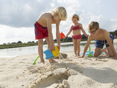 Kinderen spelen op het strand van het recreatiemeer van vakantiepark Landal Dwergter Sand