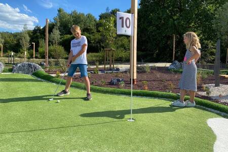 Kinderen aan het golfen op de minigolfbaan op vakantiepark Landal Forest Resort Your Nature