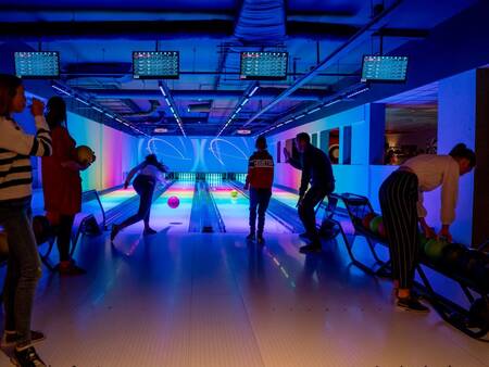 Mensen bowlen op de glow in de dark bowlingbaan van Landal Landgoed 't Loo