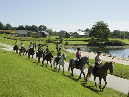 Mensen te paard aan het paardrijden langs het meer bij vakantiepark Landal Village l'Eau d'Heure