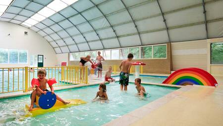 Kinderen zwemmen in het peuterbad in het overdekte zwembad van vakantiepark Molecaten het Landschap