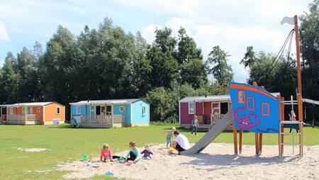 Chalets van het type "Pioen" op een veldje met speeltuin op vakantiepark Molecaten Park Flevostrand