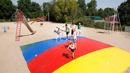 Kinderen springen op de airtrampoline in een speeltuin op vakantiepark Molecaten Park Rondeweibos