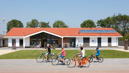 Kinderen fietsen voor de supermarkt van vakantiepark Molecaten Park Rondeweibos