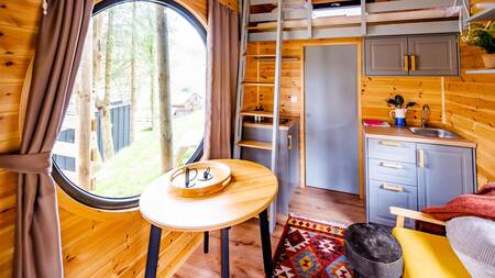 Eettafel, keuken en bed in een tiny house op Nature Parc Saint Hubert