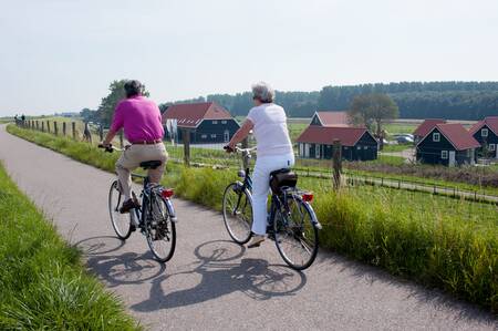 Man en vrouw aan het fietsen op de dijk langs Oosterscheldepark De Stelhoeve