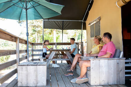 Gezin zit op de veranda van een safaritent op vakantiepark RCN les Collines de Castellane
