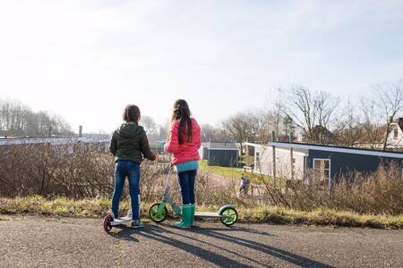 2 kinderen op stepjes voor chalets op vakantiepark RCN Toppershoedje