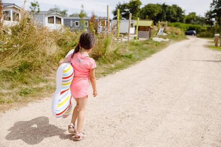 Meisje wandelt over een pad langs chalets op vakantiepark RCN Toppershoedje