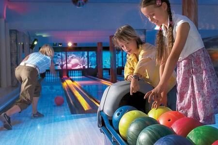 Gezin is aan het bowlen op de bowlingbaan van Roompot Vakantiepark Aquadelta