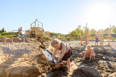 Kinderen spelen met water en zand in de speeltuin van vakantiepark Ackersate